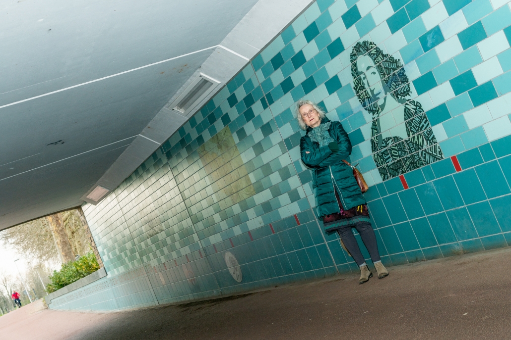 Kunstenares Louise Hessel poseert bij beeltenis Spinoza onder de Spinozabrug.